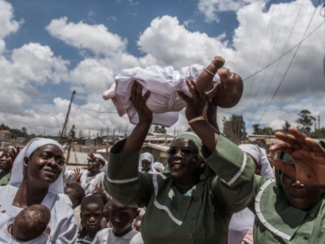 Church members carry newborn twin girls to induct them as new members of the Neema indigenous church in February 2016 in Nairobi. Photo: AFP/FREDRIK LERNERYD